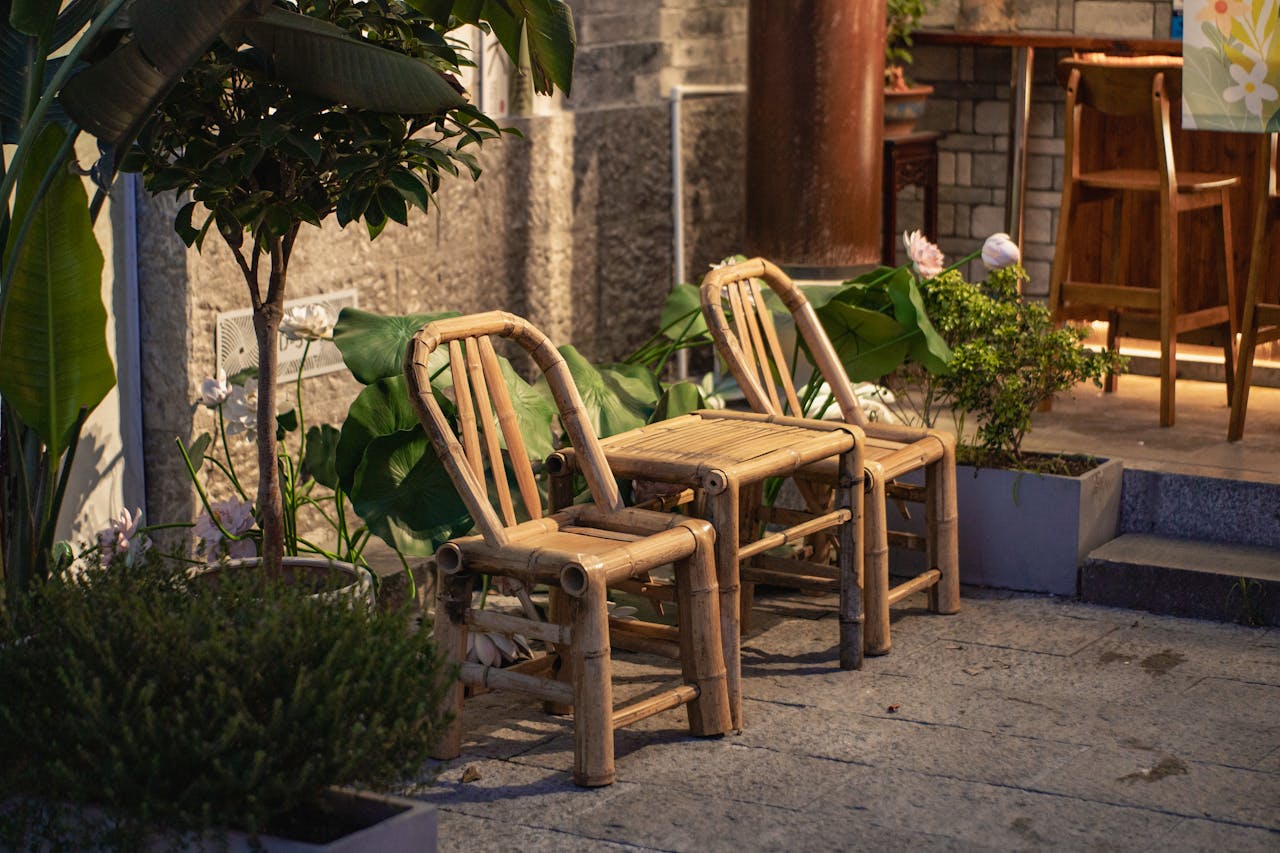 Charming bamboo chairs and table in a serene outdoor garden setting with warm evening lighting.